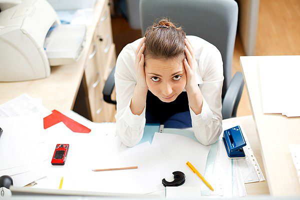 woman-holding-head-over-papers woman holding head over papers