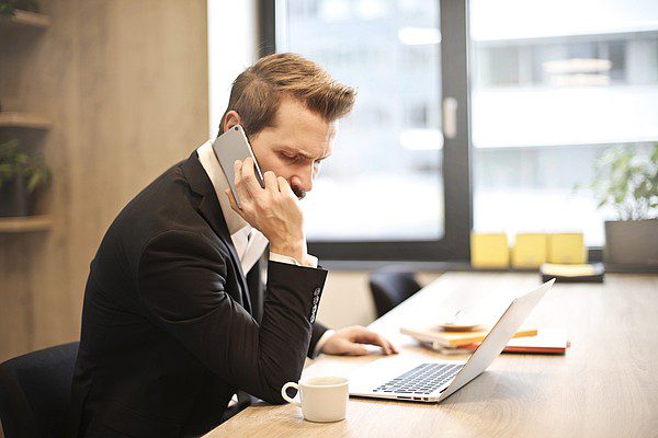 man-on-call-with-laptop-and-coffee-on-table man on call with laptop and coffee on table